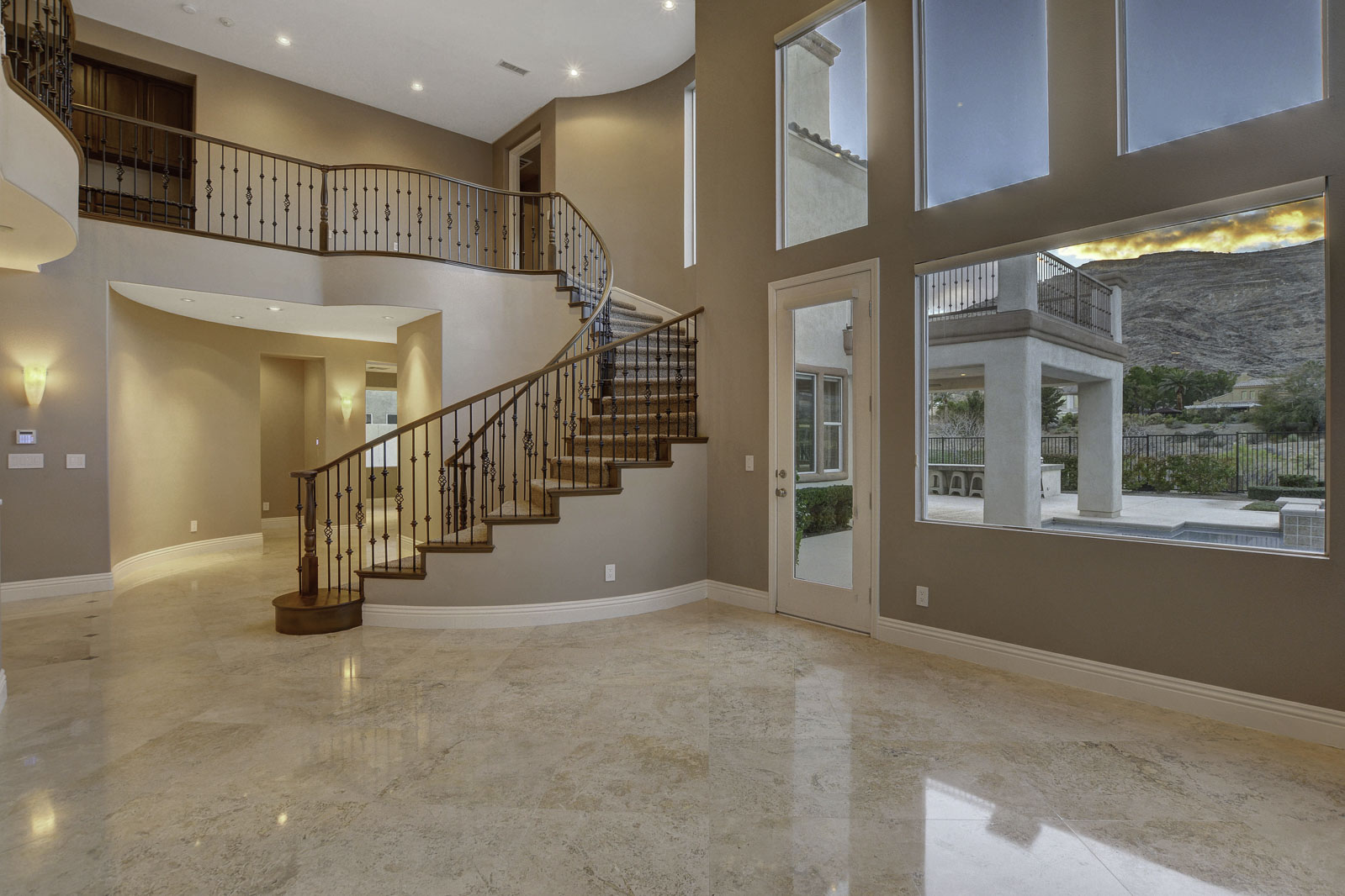 Two-story entry with curved staircase and premium stone flooring