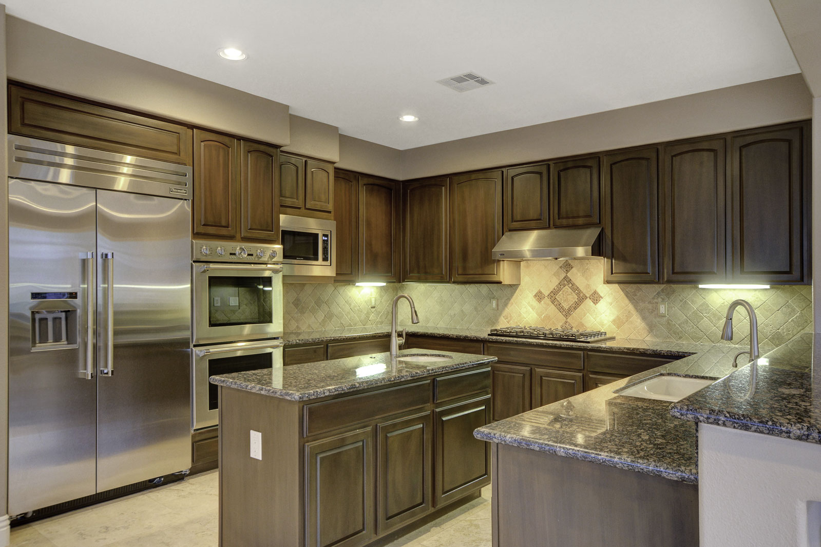 Luxury kitchen with wood cabinetry, stone countertops and stainless steel appliances