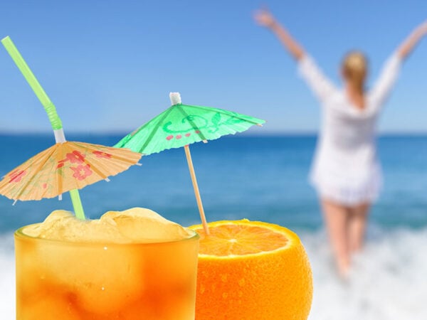 woman enjoying the view of the ocean with umbrella cocktail drinks because she hired a property management company