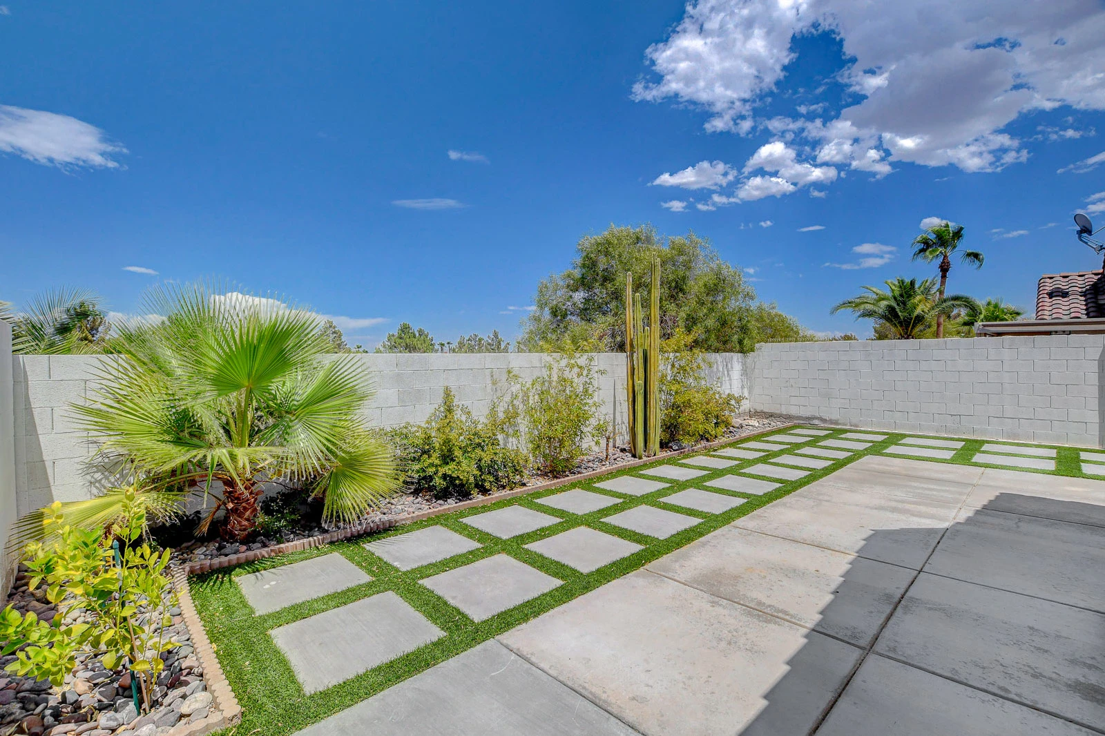 Green Valley Ranch rental backyard with artificial turf, concrete pavers, desert plants, palms and block walls