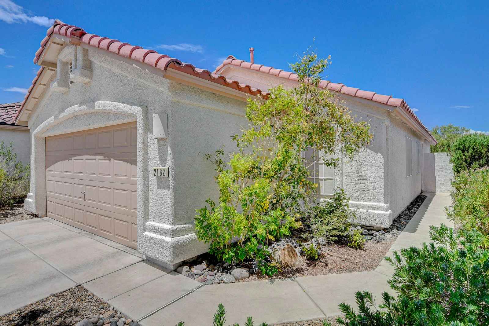 Remodeled single-story stucco rental home with tile roof and attached garage in a gated Green Valley Ranch community