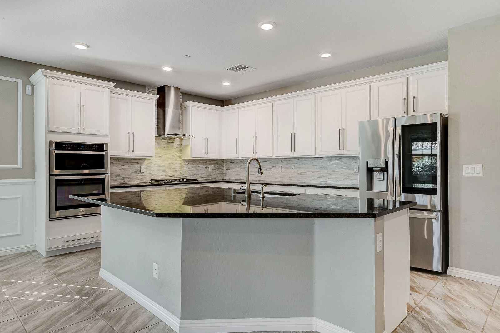 Updated white kitchen with a granite island and stainless steel appliances in a Las Vegas rental property