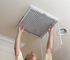 Resident replacing an HVAC air filter in a ceiling return grille